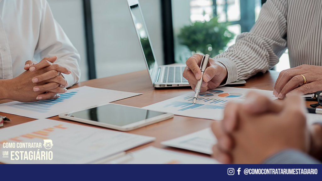 Três pessoas numa reunião de negócios assinando o documento do Termo de Compromisso de Estágio.