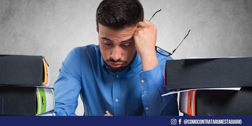 homem com uma pilha de trabalho em sua mesa, refletindo sobre a possibilidade de mudar de emprego.